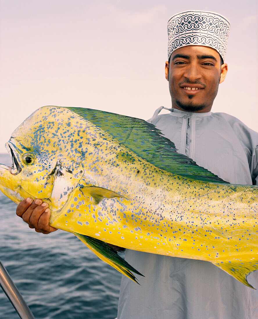 OMAN, Muscat, man holding mahi mahi fish, portrait