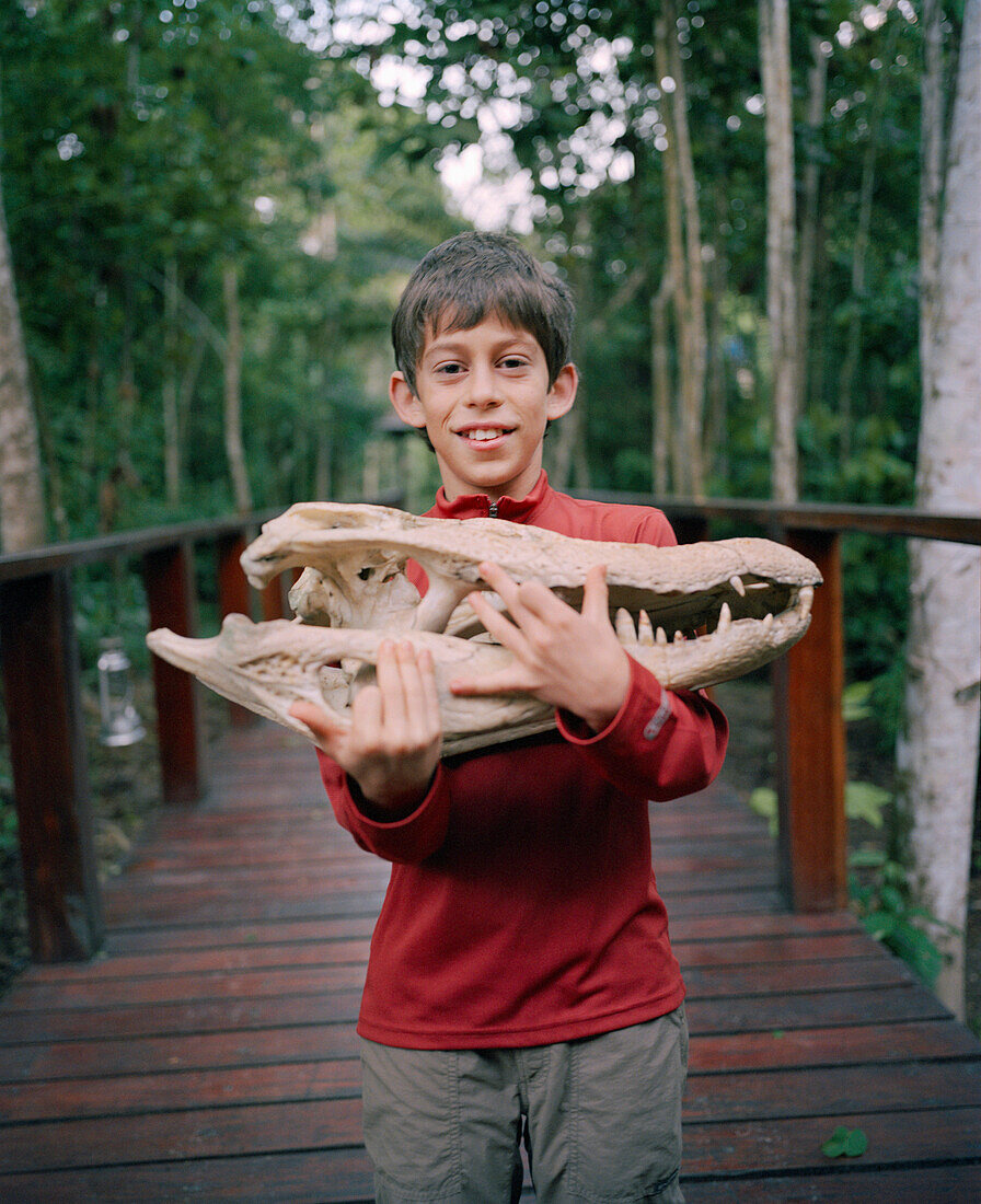 PERU, Amazon Rainforest, South America, Latin America, portrait of Asa Conover carrying a Cayman skull at the Posada Amazonas Lodge.