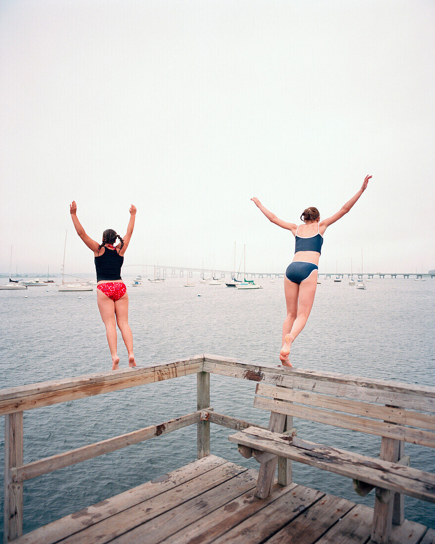 USA, Rhode island, rear view of women jumping off the pier into water