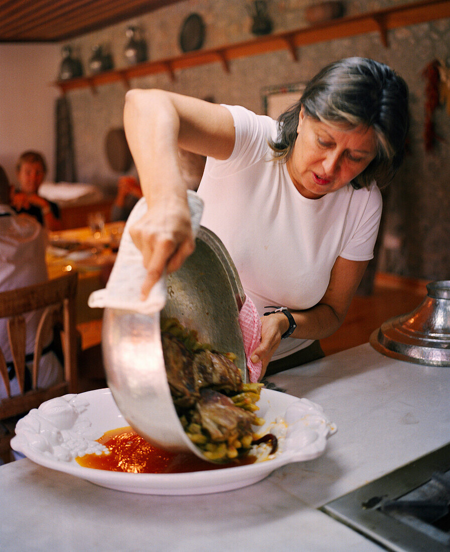 TURKEY, chef, writer, Engis Akin pouring a Turkish cuisine in a large plate in her kitchen.