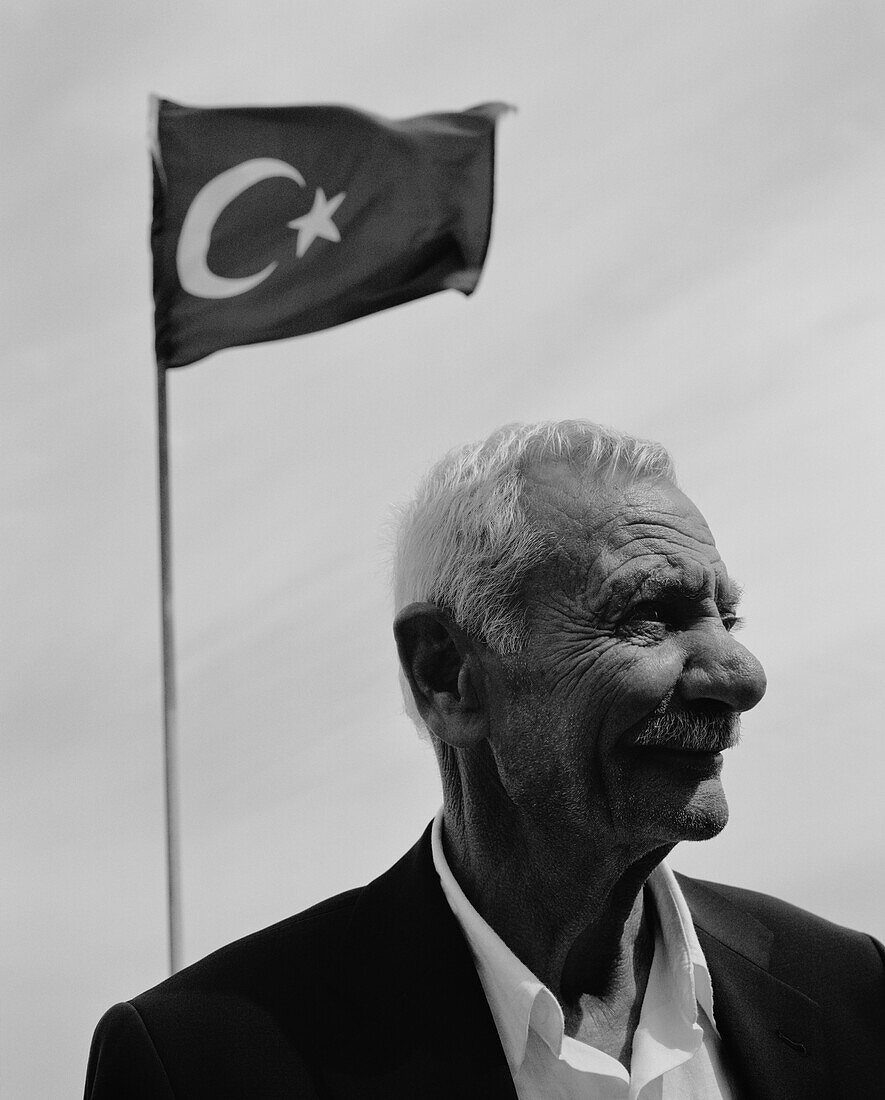 TURKEY, Istanbul, mature fisherman smiling with Turkish flag in the background