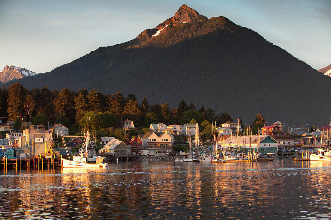 ALASKA, Sitka, a peaceful view of homes and fishing boats along the shore in Sitka Harbor at sunset, Mount Verstovia peak in in the distance