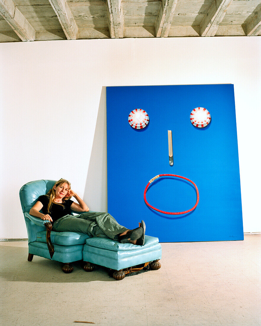 USA, Arizona, female artist relaxes in armchair next to her painting starry eyes, Winslow