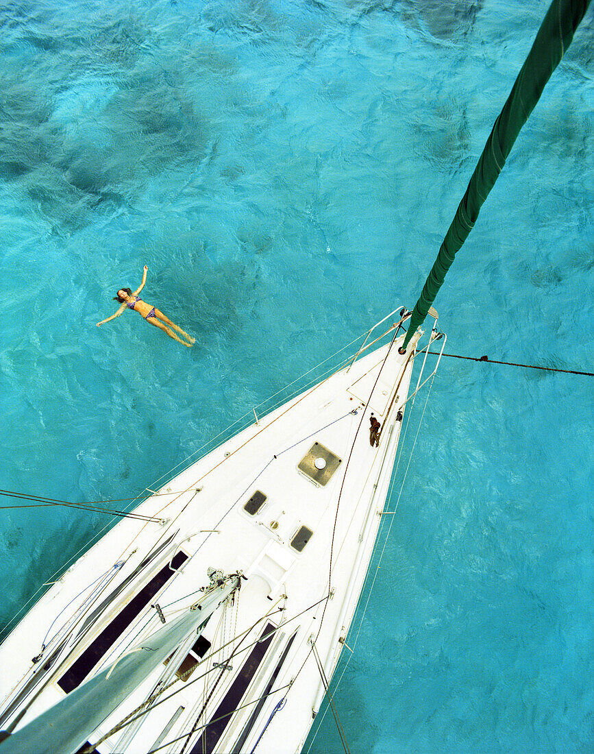 ARUBA, woman swimming in Caribbean Sea by a sailboat, Palm Island