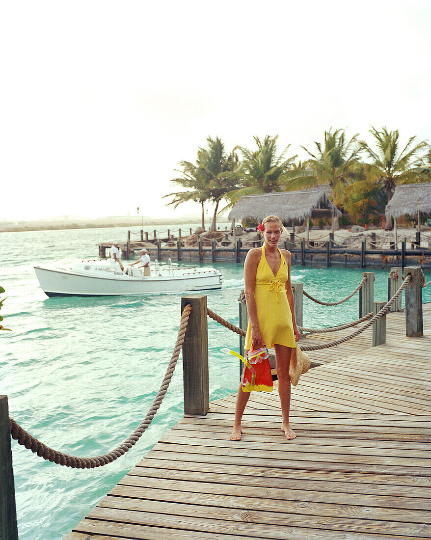 ARUBA, portrait of young woman standing on a dock with her snorkel gear, Renaissance Island