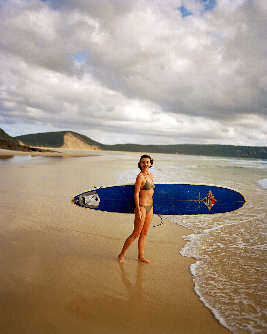 AUSTRALIA, Queensland, Noosa Heads, portrait of a surfer woman smiling before she gets into the water, 40 Mile Beach