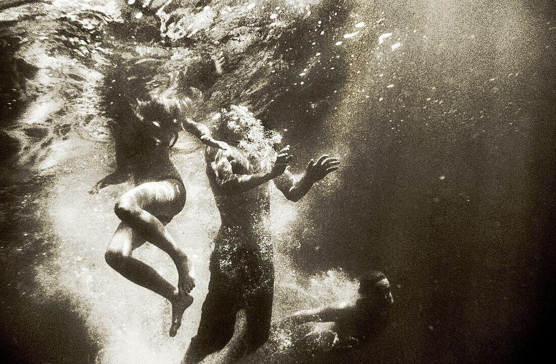 USA, California, man and women swimming underwater in the Forks of Salmon River (B&W)