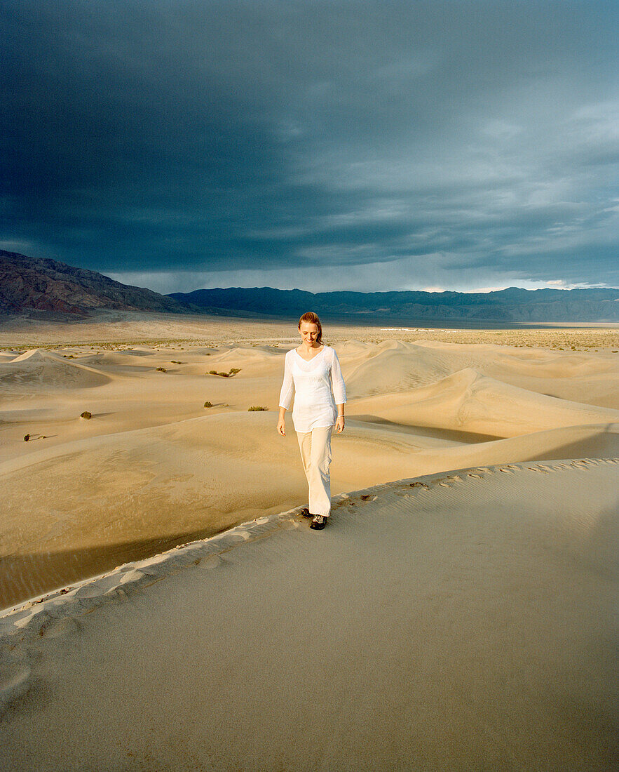 USA, California, young woman standing on sand dune, Stovepipe Wells, Death Valley National Park