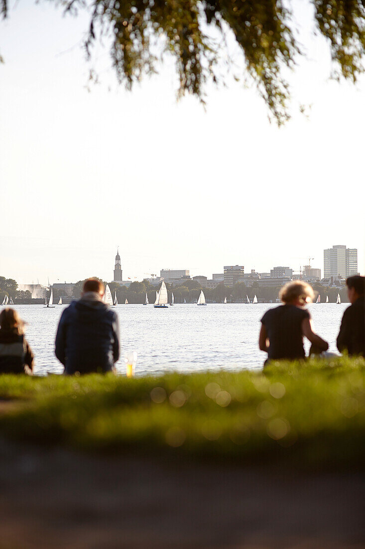 People sitting on a seawall at Outer Alster Lake, Hamburg, Germany