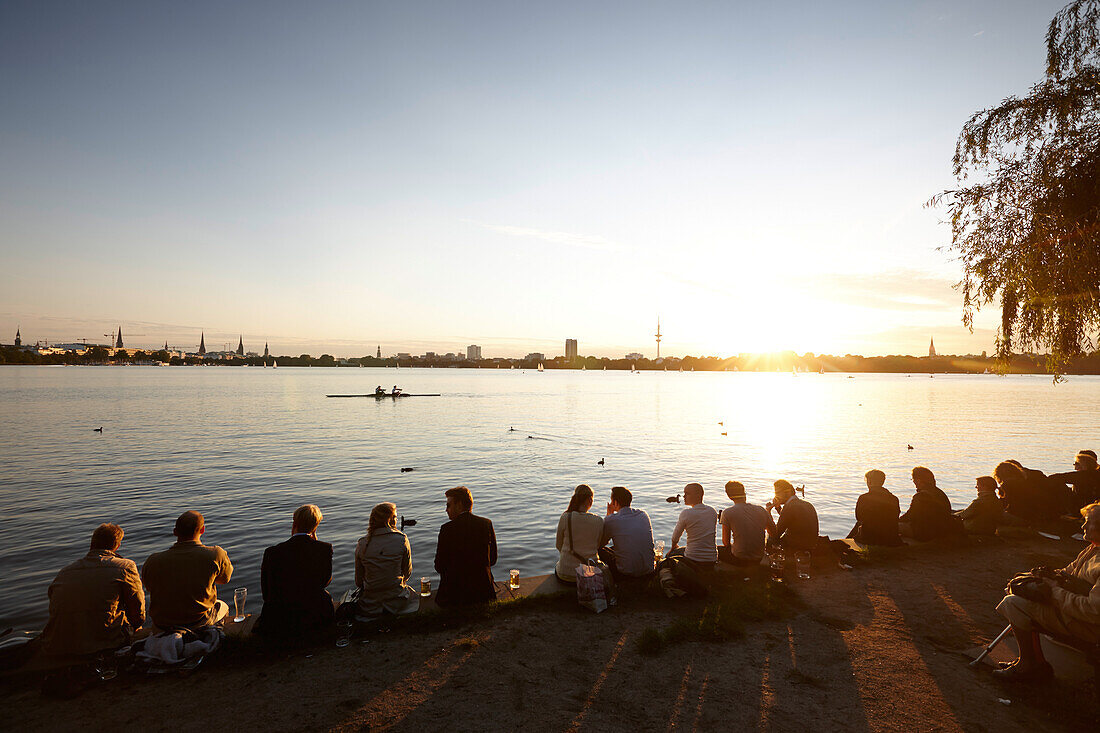 People sitting on seawall at Alsterperle cafe and bar, Eduard-Rhein-Ufer 1, Outer Alster Lake, Hamburg, Germany