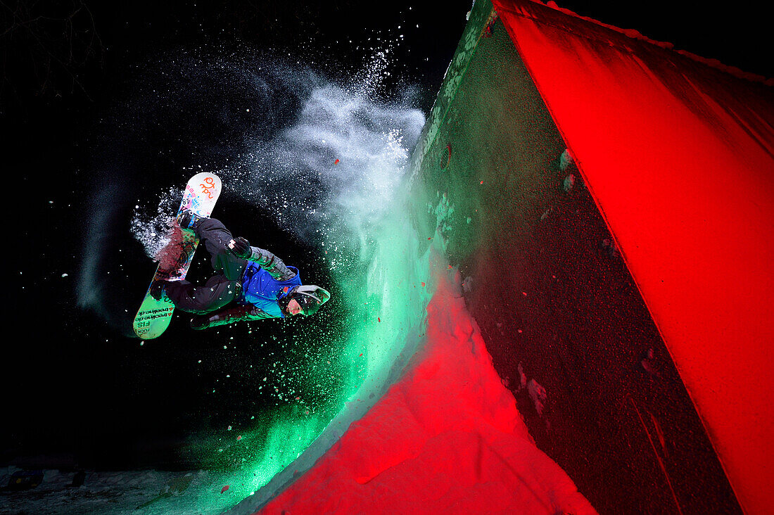 Junger Mann springt nachts mit Snowboard an Schanze, Rosenheim, Oberbayern, Bayern, Deutschland