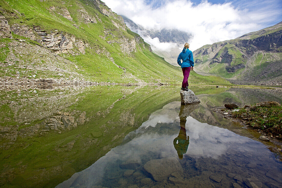 Junge Frau steht auf einem Stein im Fluss Soca, Alpe-Adria-Trail, Tolmin, Slowenien
