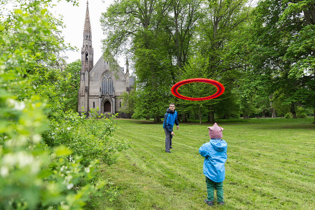 Vater und Sohn spielen Frisbee, Schlosskirche im Hintergrund, Schloss Kröchlendorff, Kröchlendorff, Uckermark, Brandenburg, Deutschland