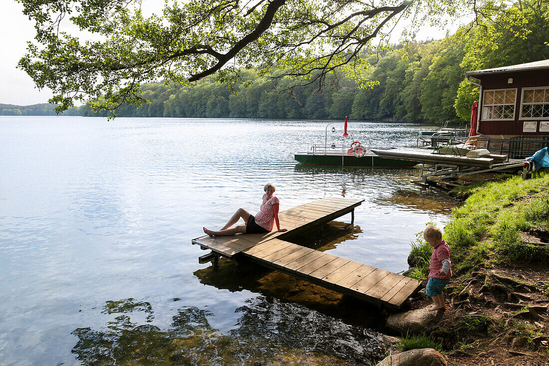 Mother and son on a jetty at lake Schmaler Luzin, Feldberger Seenlandschaft, Mecklenburg-Western Pomerania, Germany