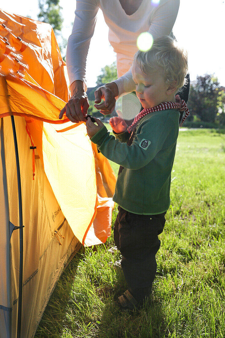 Mother and son (2 years) putting up a tent, Wesenberg, Mecklenburg-Western Pomerania, Germany