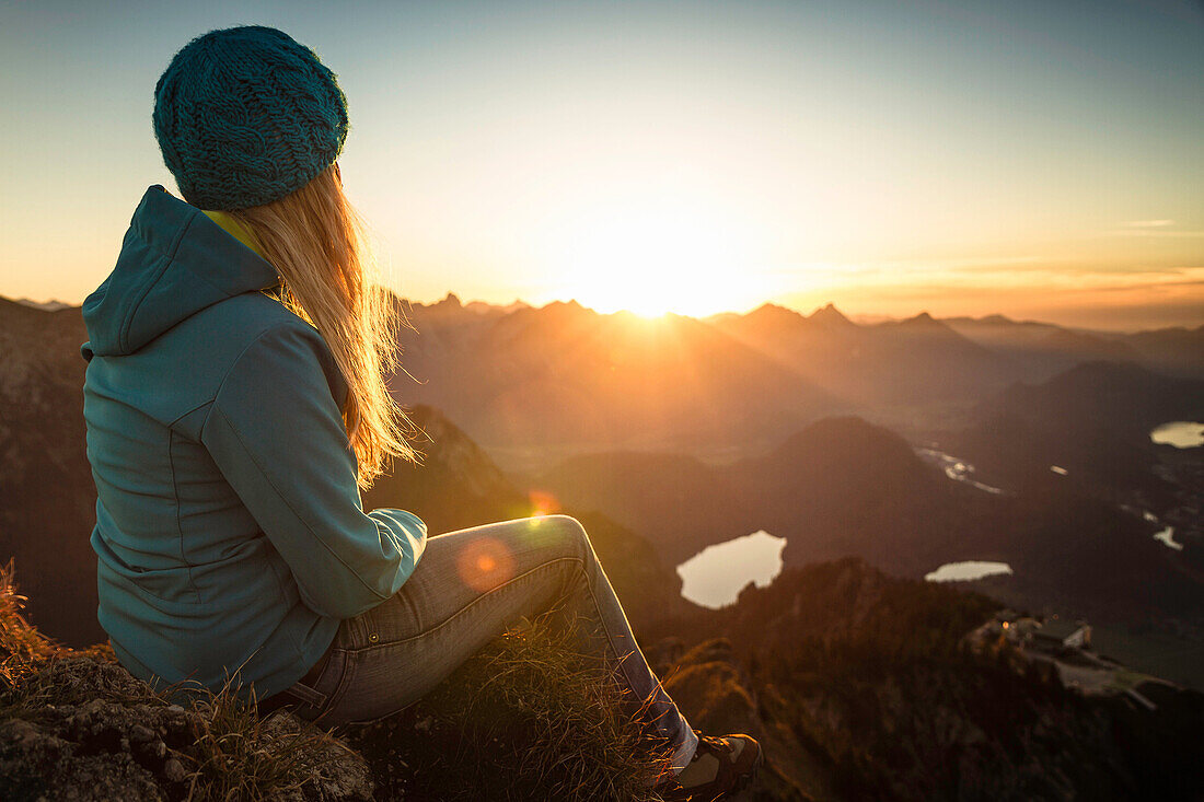 Hiker sitting on rocky hilltop. Branderschrofen, Tegelberg