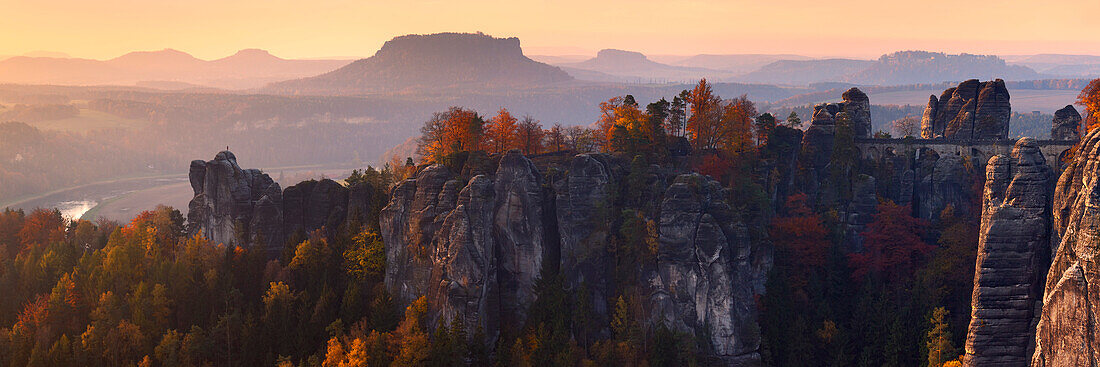 The first sunlight reaches the Bastei Bridge and the mountain tops of the Elbe Sandstone Massif in Autumn, Saxon Switzerland, Saxony, Germany