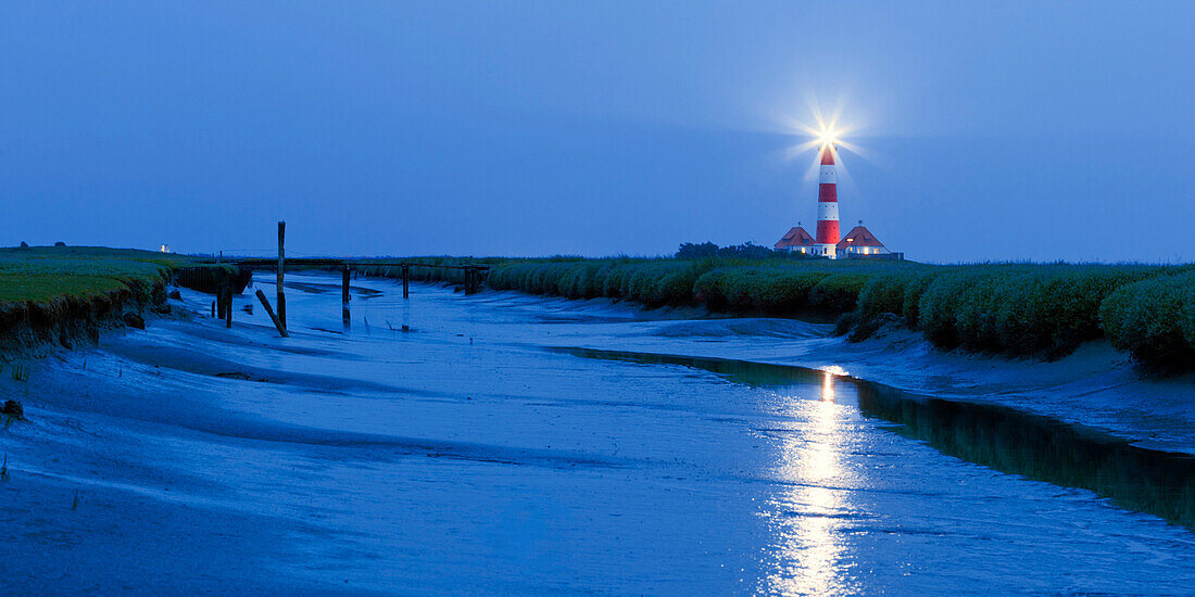 Panorama of the lighthouse Westerheversand with tide-way in the foreground at dusk, Schleswig-Holstein, Germany