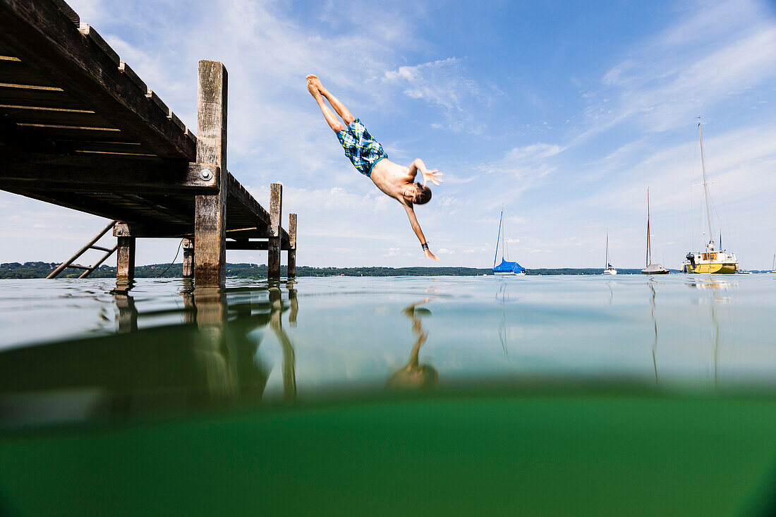 Boy jumping into lake Starnberg, Bavaria, Germany