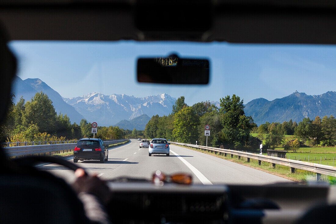 Blick durch eine Windschutzscheibe auf Autobahn A95 mit Wettersteingebirge im Hintergrund, Bayern, Deutschland