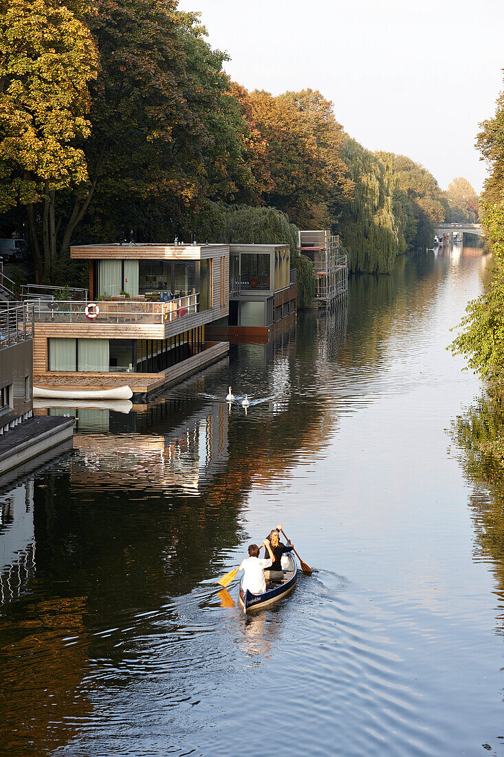 Couple canoeing on Eilbek canal, houseboats in background, Hamburg, Germany