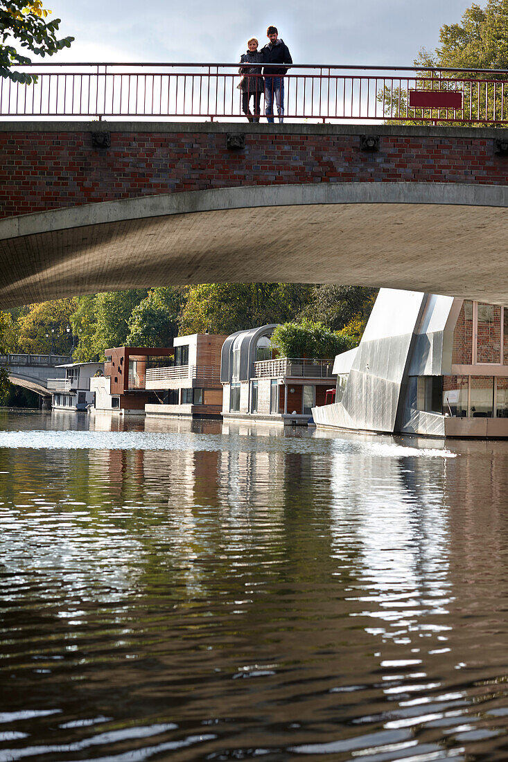 Couple on a bridge above Eilbek canal, houseboats in background, Hamburg, Germany