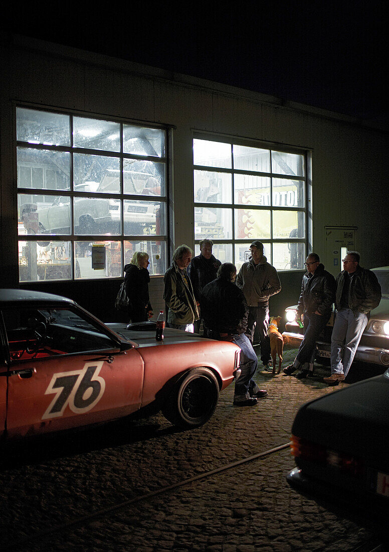 Group of people with modern classic cars in front of a garage, Hamburg, Germany