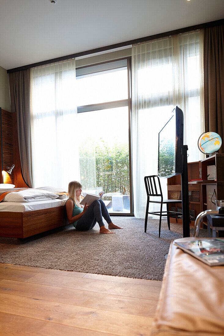 Woman sitting on floor of a hotel room, Hafencity, Hamburg, Germany