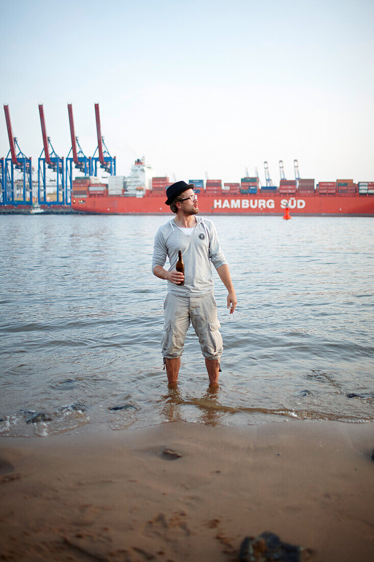 Guest on the beach near Cafe Strandperle in Hamburg-Oevelgoenne, the HHLA container terminal is situated on the opposite bank of the Elbe, Hamburg harbour, Hamburg, Germany