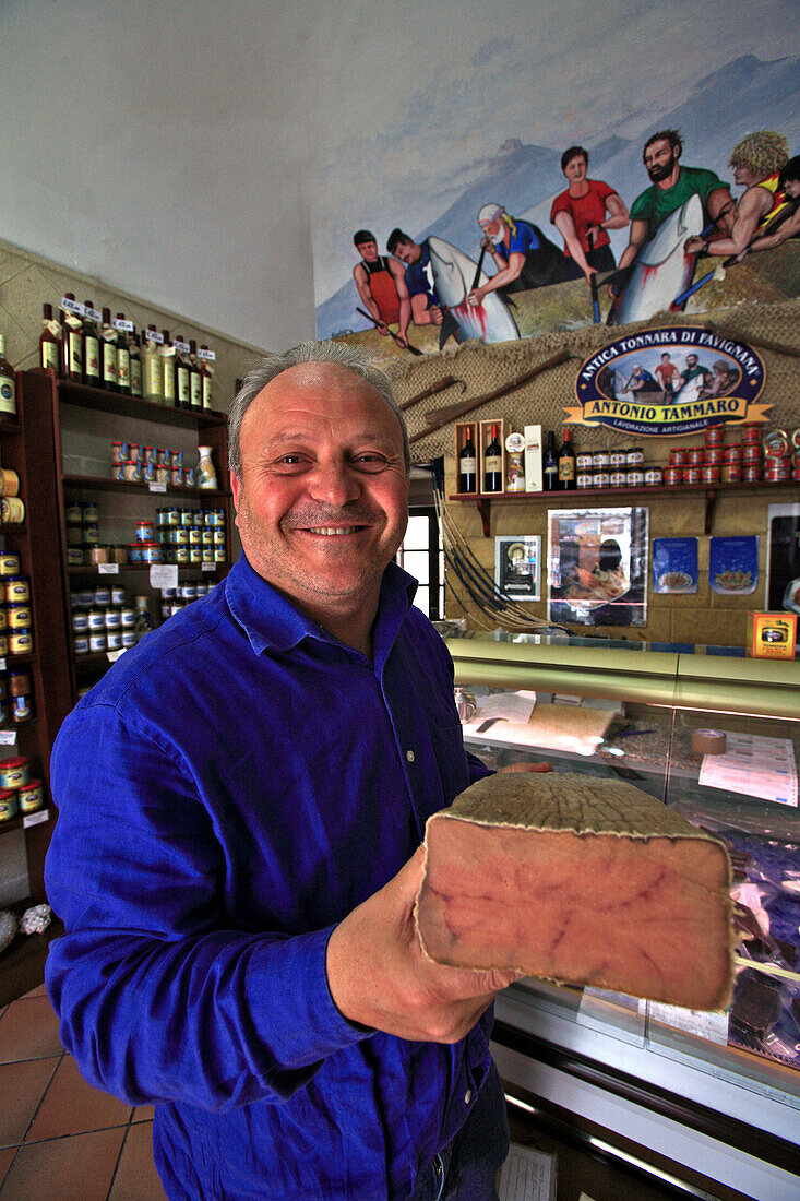 Italy, Sicily,  Aegadian Islands, Favignana Island, Grocer's shop, Grocer holding a huge tuna steack