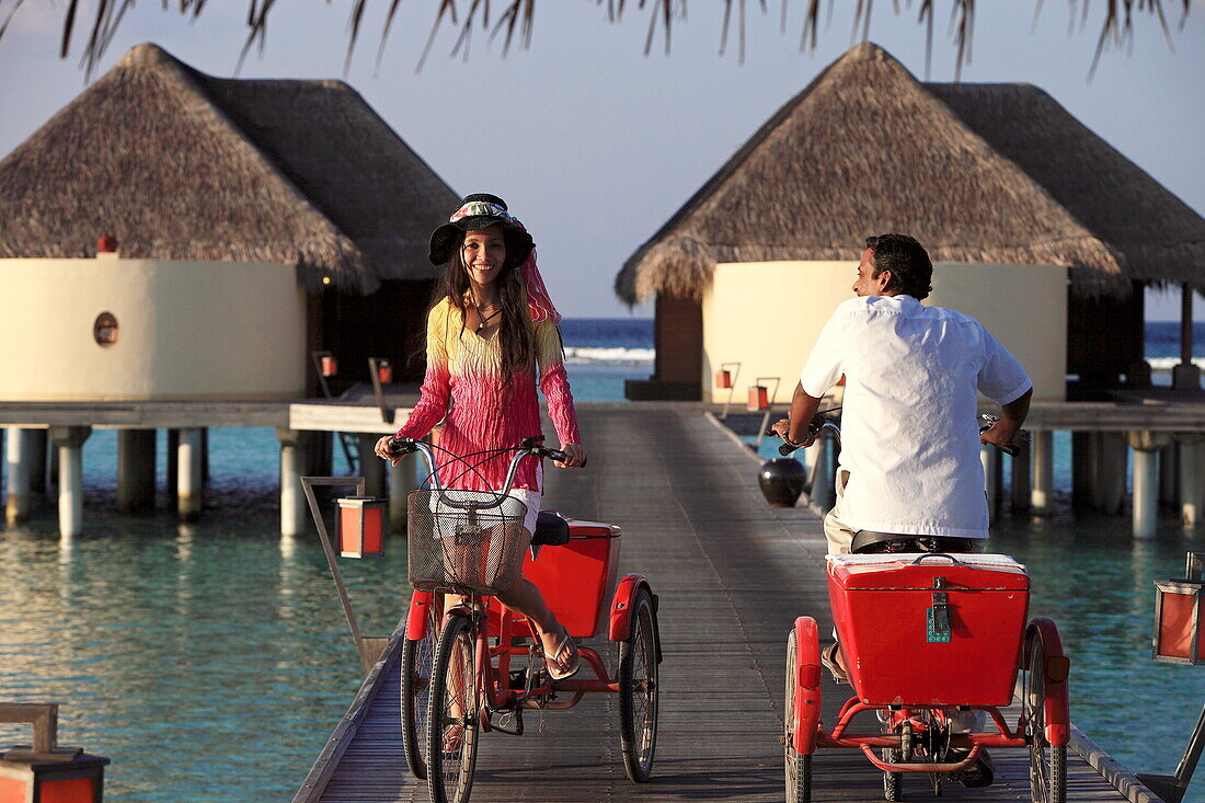 Republic of the Maldives, Lhaviyani Atoll,  Kanuhura Hotel, landing stage and two persons riding tricycles