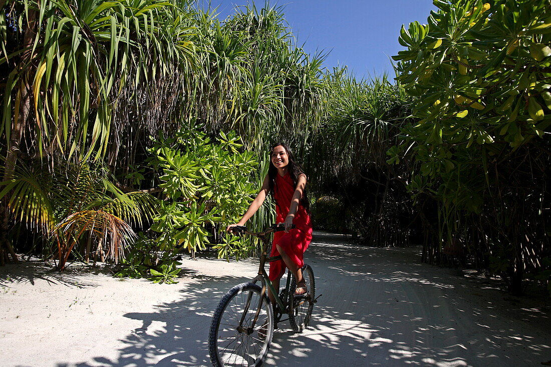 Republic of the Maldives, Lhaviyani Atoll,  Kanuhura Hotel, Woman riding a bicycle