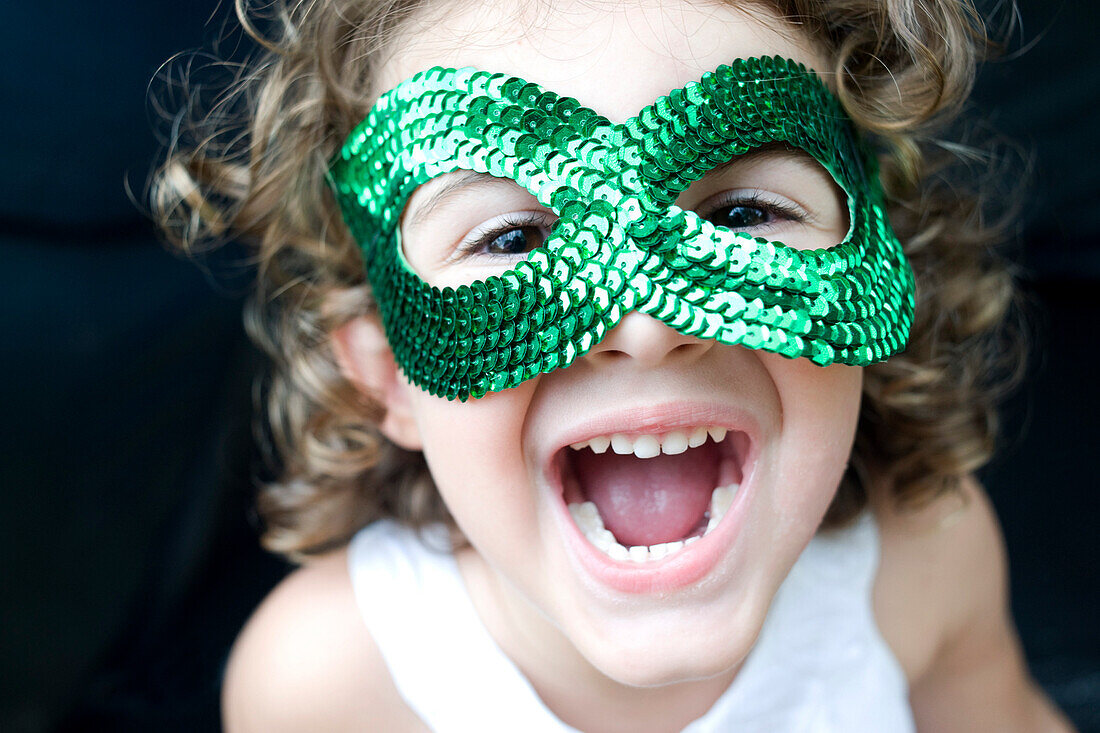 Young girl wear a green glitter mask ans smiling with open mouth