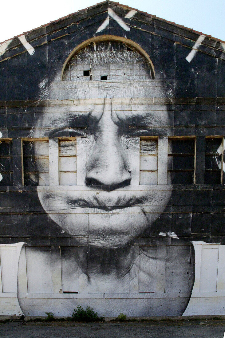 France, Arles, Facade of a warehouse decorated with a giant black and white photography of an old woman