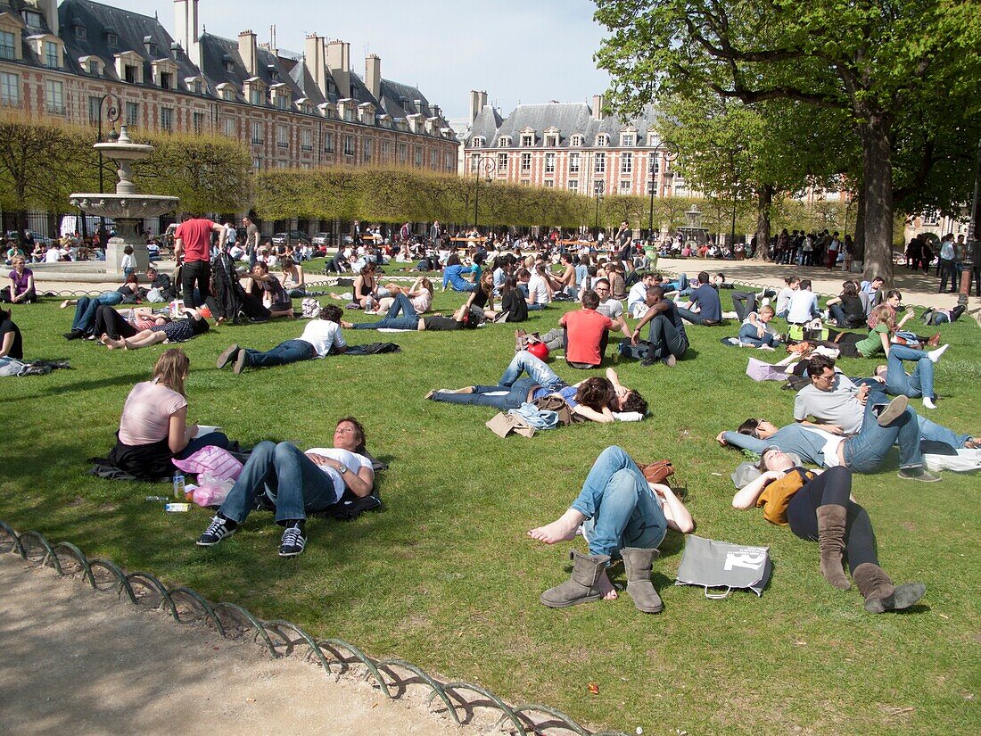 France, Marais District, The Place des Vosges, people resting under the sun, laying on the lawn