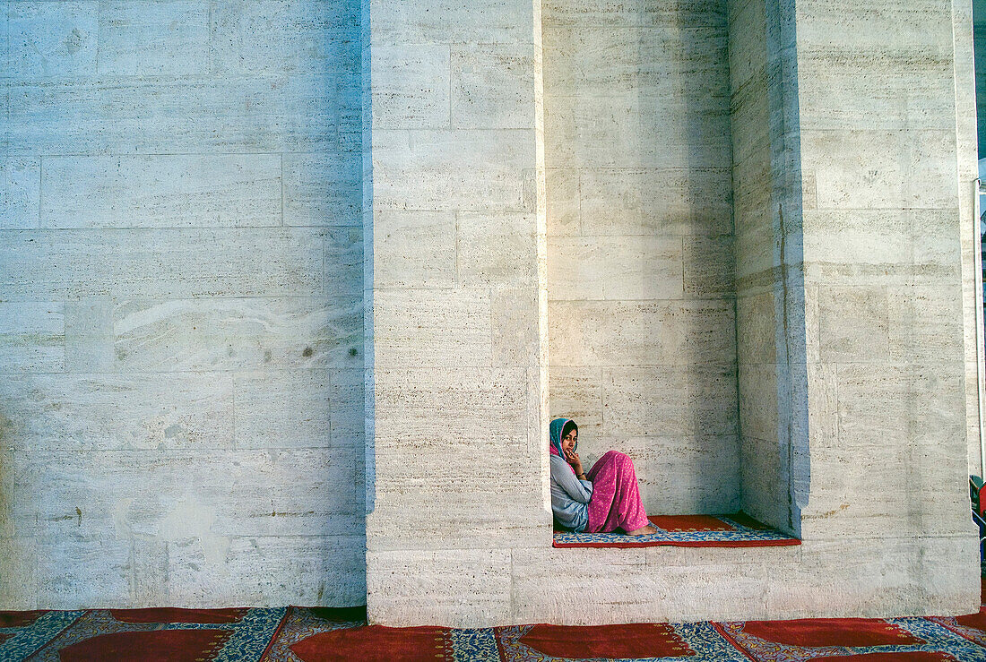 Republic of Turkey, Istanbul,  The Süleymaniye Mosque - Süleymaniye Camii, The biggest mosque of the city, young woman resting on a wall between two columns