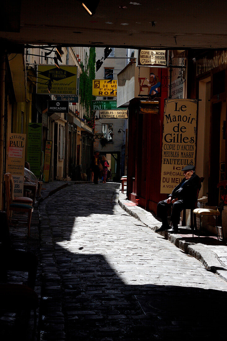 FRANCE, paris, 12e, passage du chantier, faubourg saint-antoine street, shops of makers pieces of furniture with a sitting man on a chair