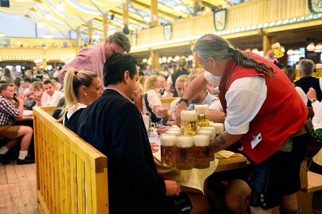 Male waiter with beer steins during  Oktoberfest festival in Munich, Germany