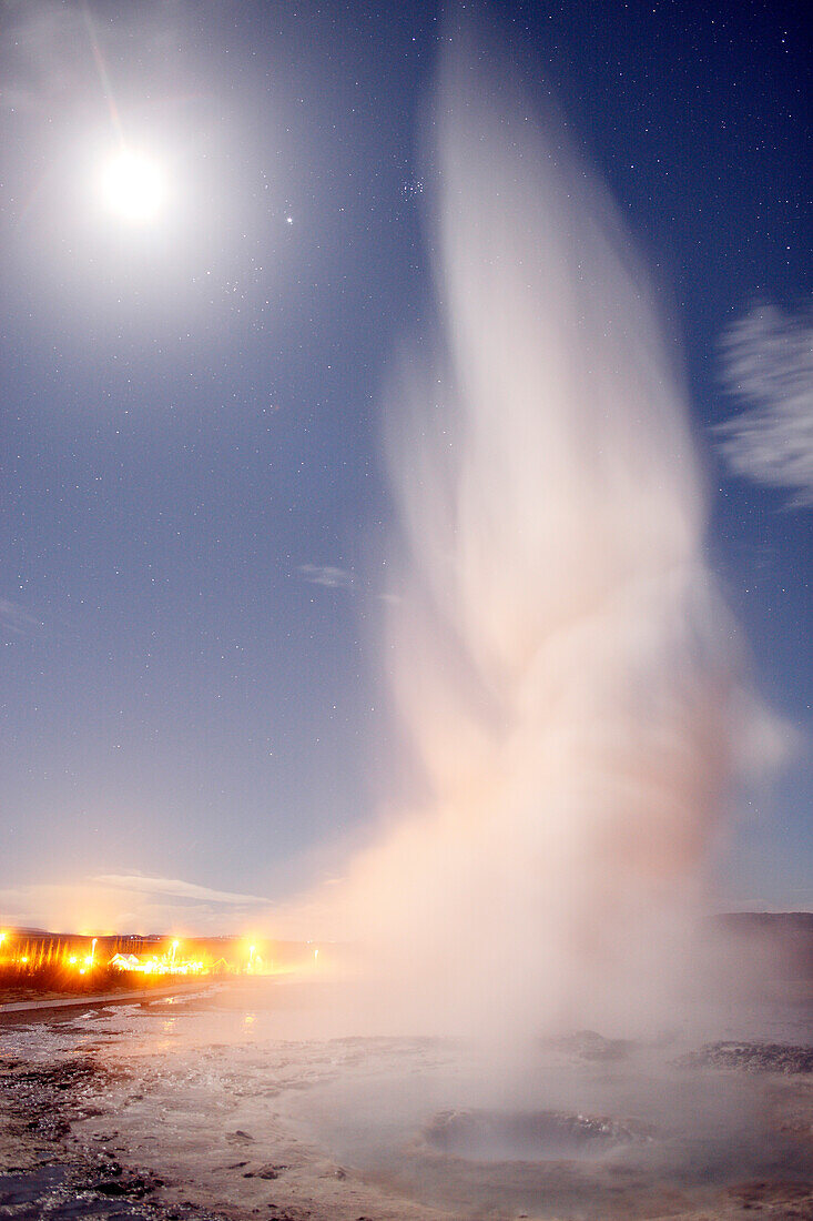 Iceland. Central region. Geysir. Strokkur geyser at night. Moon and stars in the sky.