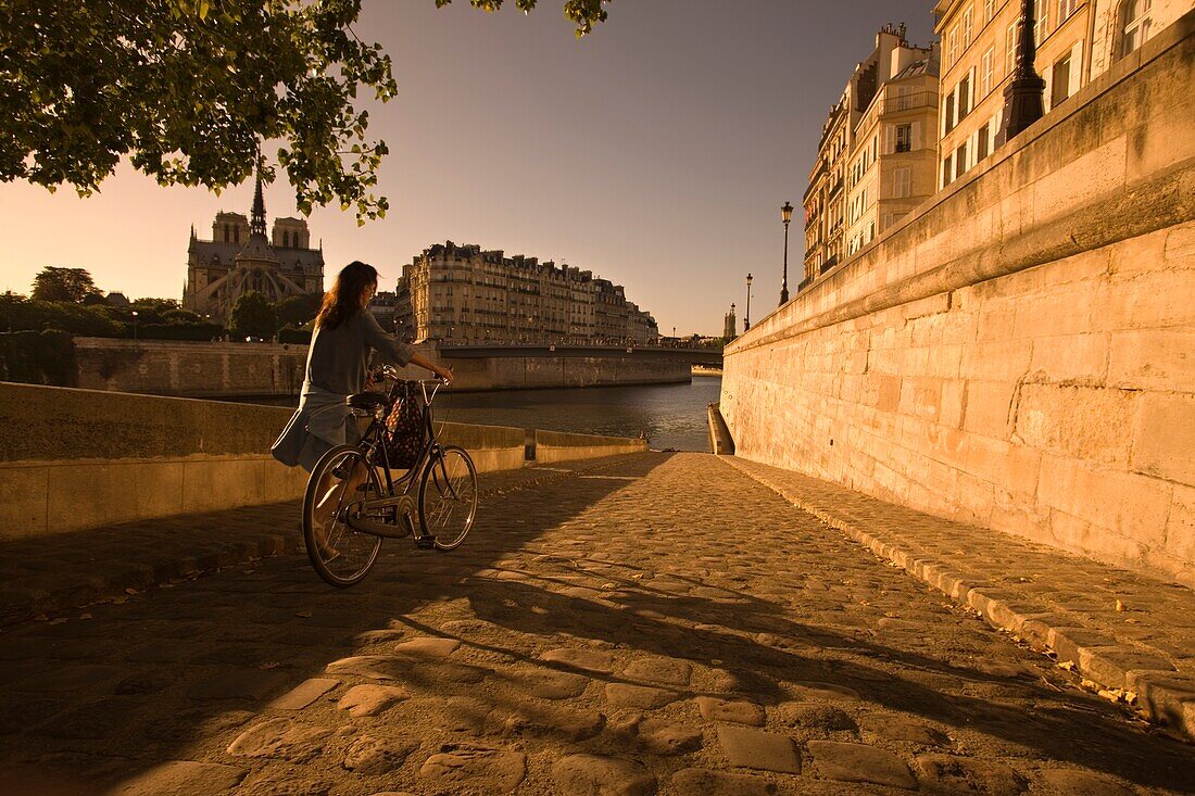 YOUNG WOMAN PUSHING BICYCLE QUAI D'ORLEANS RIVER SEINE ILE SAINT LOUISE PARIS FRANCE