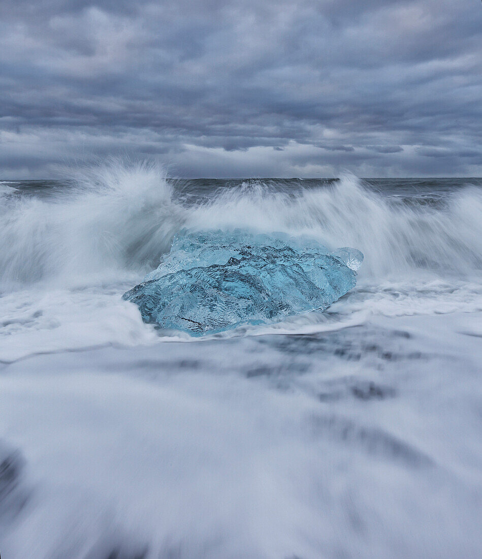 Waves from the atlantic ocean crash into ice calf from breioamerkurjokull a glacial tongue of the vatnajokull ice cap, iceland