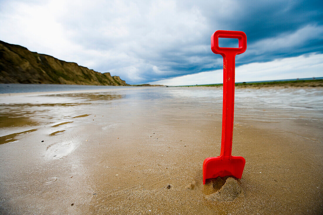 Red Plastic Spade In Sand On Beach