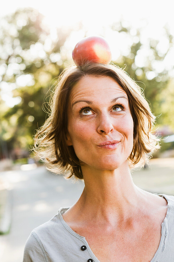 Woman balancing apple on head outdoors