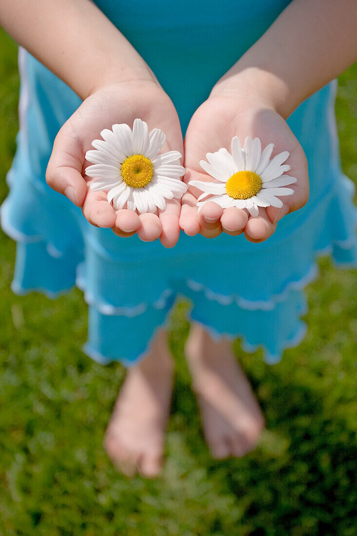 Girl Standing on Lawn Holding Daisies.