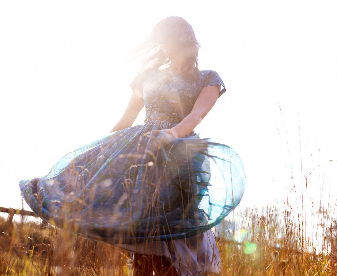 Blurry Portrait of Woman Standing in Grass Twirling Skirt