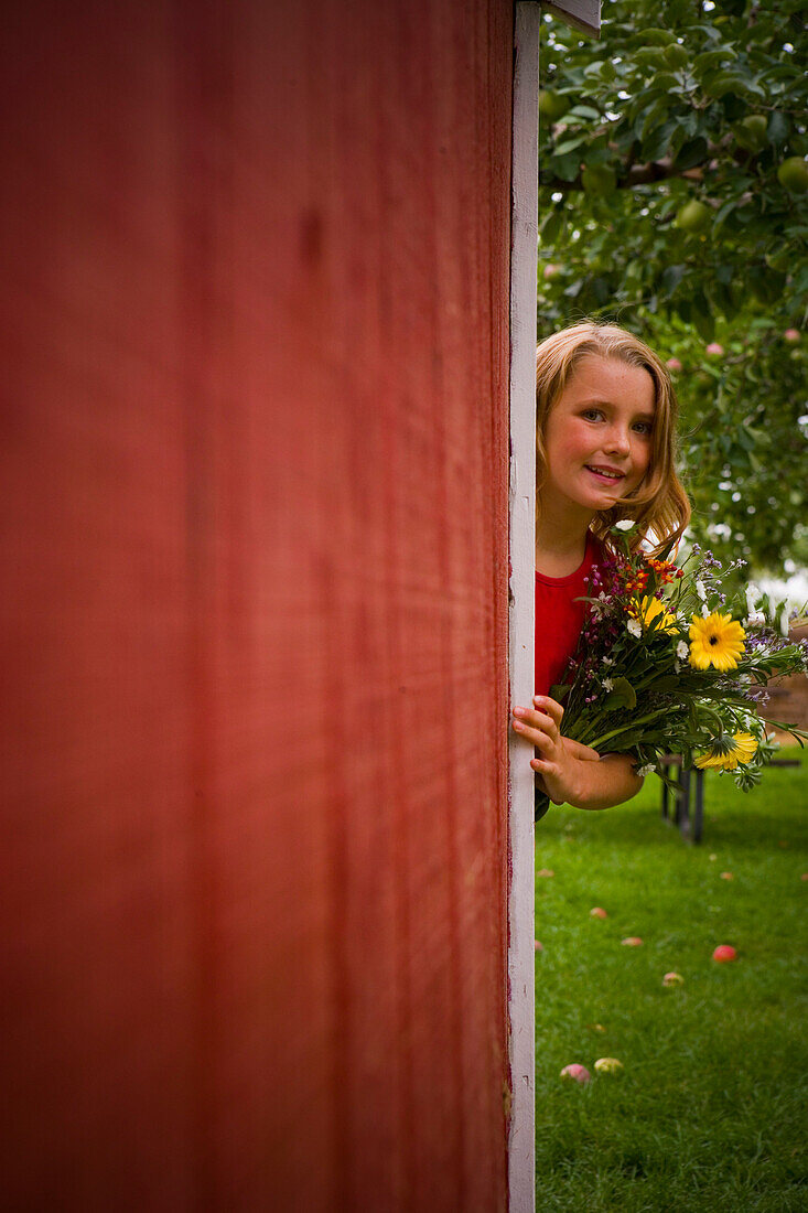 Girl with Flowers Peeking around Shed