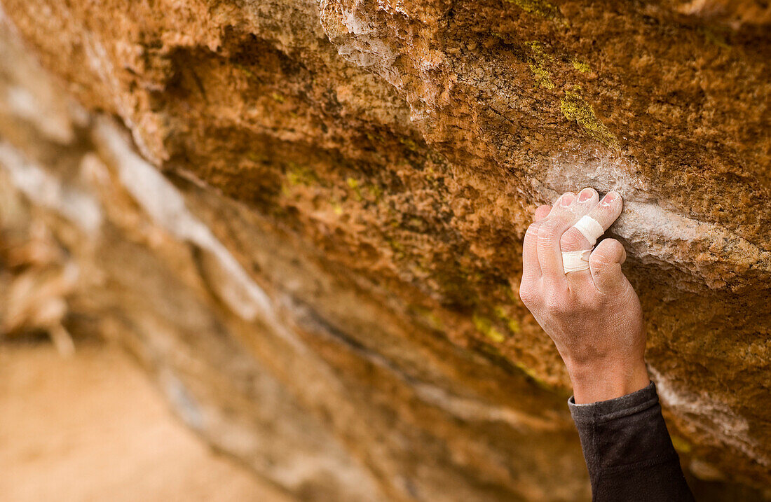 Mans Hand Clinging to Rock while Climbing