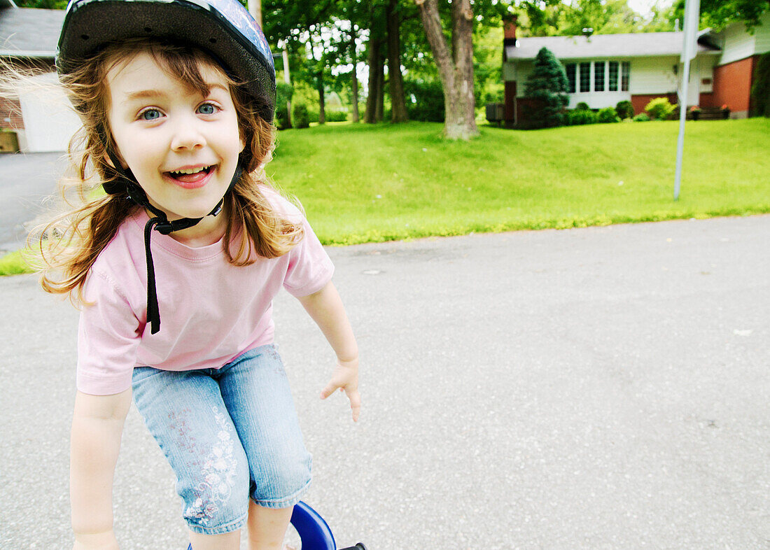 Smiling blond girl with helmet standing on bike, Otterburn Park, Quebec
