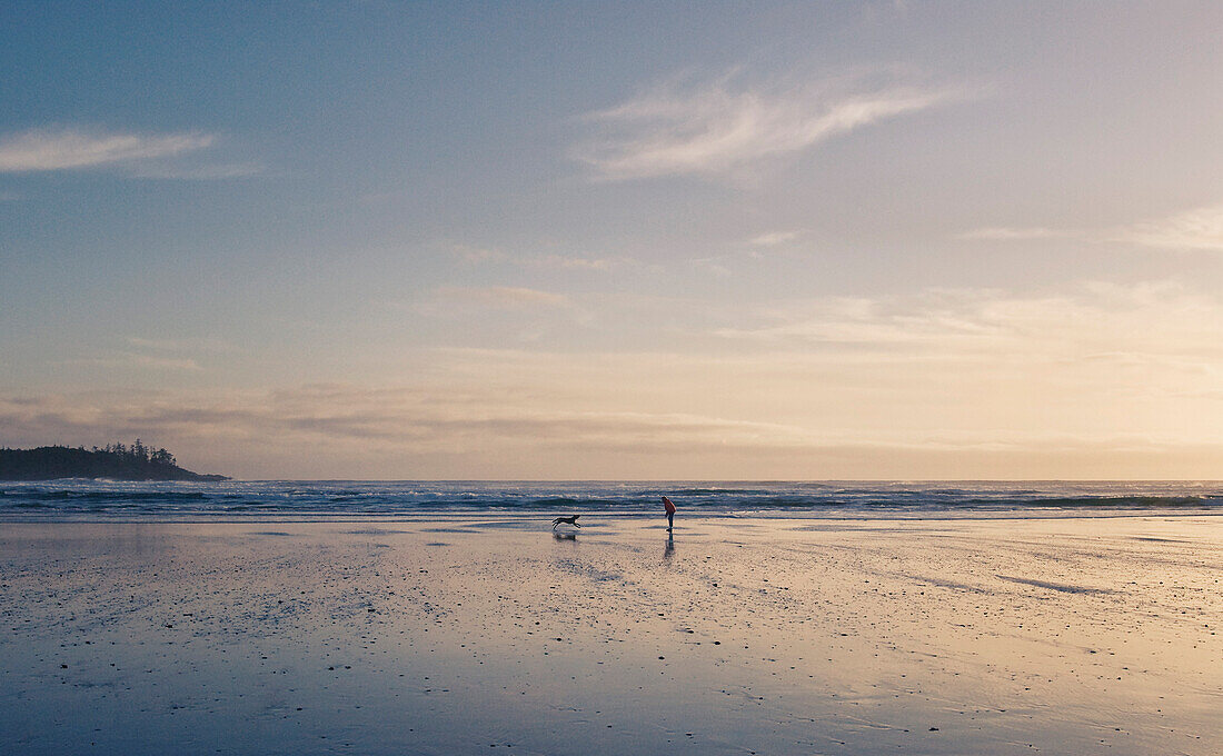Woman and Dog playing on Beach at Sunset, Chesterman Beach, West Coast of Vancouver Island, British Columbia