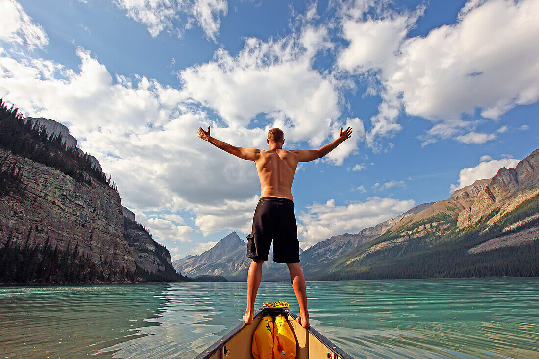 Man standing on the bow of his canoe, Maligne Lake, Jasper National Park, Alberta